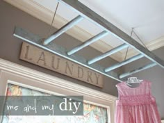 a pink dress hanging on a clothes line in front of a sign that says laundry