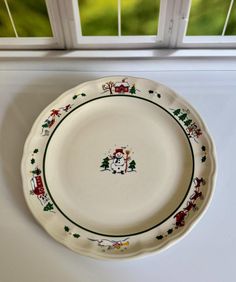 a white plate with christmas decorations on it sitting in front of a window sill