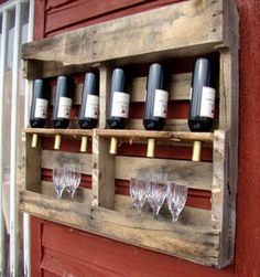 several bottles of wine are sitting on a wooden rack in front of a red door