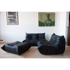 a living room with black leather furniture and pictures on the wall