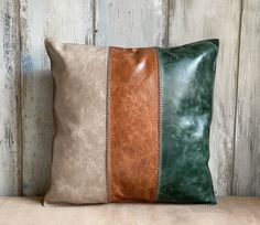 two different colored leather pillows sitting on top of a wooden table