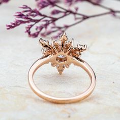 a close up of a ring on a table with purple flowers in the back ground