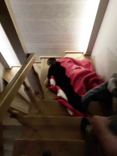 a person laying down on the stairs in a room with wood floors and white walls