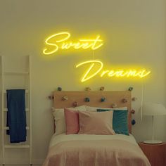 a neon sign that says sweet dreams above a bed