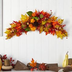 an arrangement of fall leaves and pumpkins on a mantle