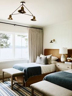 two beds in a bedroom with striped rugs and lamps on either side of them