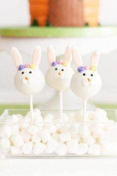 three bunny lollipops sitting on top of marshmallows