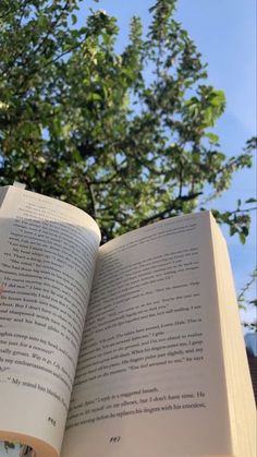 an open book sitting in front of a tree