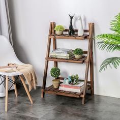 a wooden shelf with books and plants on it next to a white chair in a room