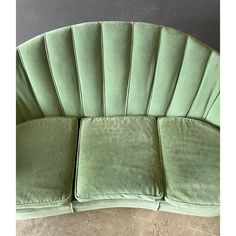 an upholstered green velvet sofa with pleated backrests and rounded cushions