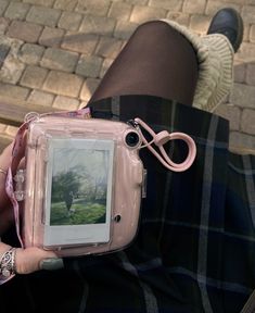 a person is holding a pink camera with a picture on the screen in their hand