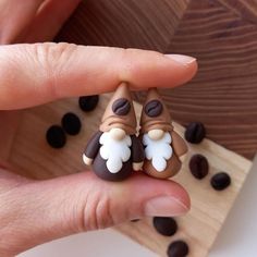 a person is holding two small figurines in their hand, with coffee beans scattered around them