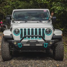 a jeep is parked on the side of a dirt road in front of some trees