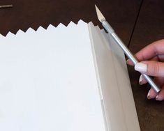 a person holding a pencil near a piece of paper with a hole cut in it