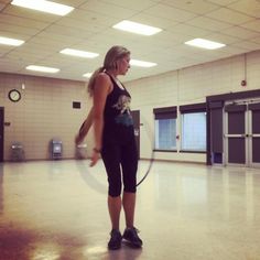 a woman is holding a hula hoop in an empty room