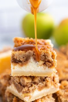 a stack of dessert bars with caramel sauce being drizzled over them