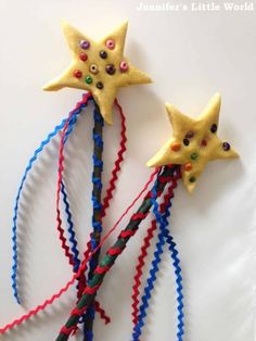 two little stars are made out of plastic beads and streamers on a white surface