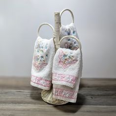 two white towels hanging from a basket on top of a wooden table next to each other