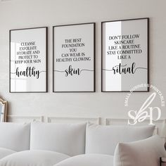 three black and white posters on the wall above a couch in a living room with pillows