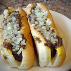 two hot dogs with onions and mustard on a plate