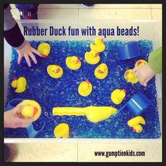 children are playing with rubber duck toys in an aquarium filled with blue water and yellow rubber ducks