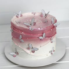 there is a pink and white cake with butterflies on it