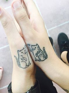 two people with matching tattoos on their hands, one has a cat and the other has a dog