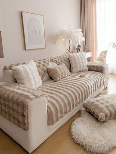 a living room filled with furniture and a white rug on top of a hard wood floor