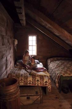 two people sitting on a bed in an attic