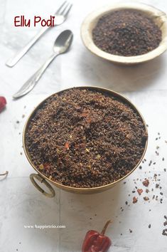 two bowls filled with chili powder next to spoons and pepper flakes on a table