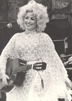 an old photo of a woman holding a guitar in front of a microphone and singing