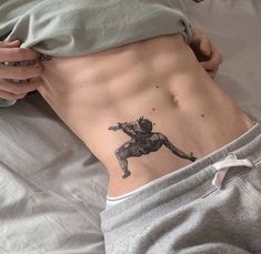 a person laying on top of a bed with a tattoo on their stomach and back