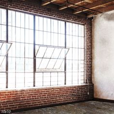 an empty room with brick walls and large windows