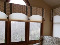 a living room filled with furniture and windows covered in roman shade shades on top of them