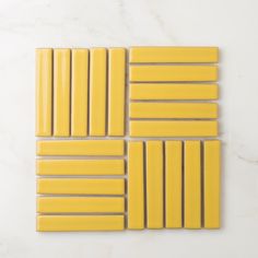 four yellow tiles laid out on a white surface