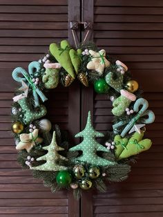 a christmas wreath hanging on the front door with green and gold ornaments around it,