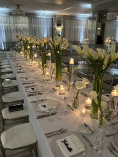 a long table is set with white flowers and candles for an elegant dinner or party