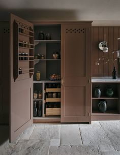 an open cabinet in the middle of a room with shelves and vases on it