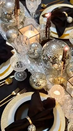 the table is set with black and gold place settings, silverware, and crystal ball centerpieces