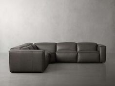 a gray leather sectional sofa in front of a white wall with no one sitting on it