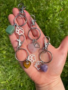 a person is holding several different charms in their hand, including one with a dog's paw on it