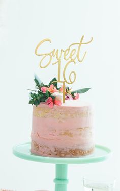 a cake with pink frosting and gold lettering on top that says sweet 16 next to a glass of champagne