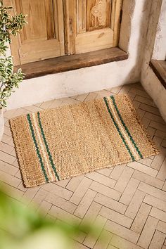 a door mat on the floor next to a potted plant