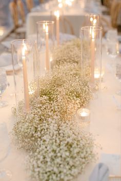 the table is set with candles and baby's breath flowers