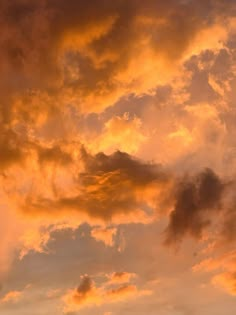 an airplane is flying in the sky at sunset or sunrise with orange and yellow clouds