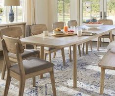 a dining room table and chairs in front of a window with an area rug on the floor