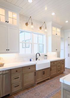 a large kitchen with white cabinets and wood flooring, along with a rug on the floor