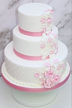 a three tiered cake with pink and white flowers