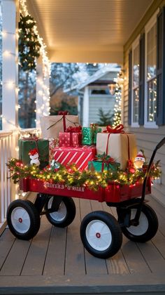 a red wagon filled with presents sitting on top of a wooden porch covered in christmas lights