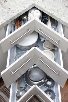 an overhead view of a kitchen drawer with pots and pans in the bottom compartment